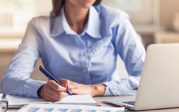 Woman writing in a pad at a desk